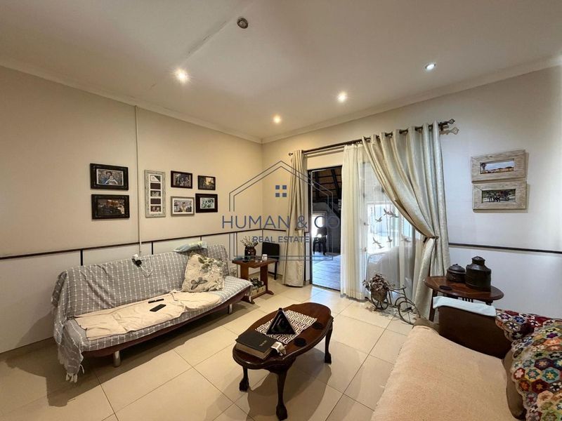 A living room featuring tiled flooring, recessed downlights, and a sliding glass door providing access to an outdoor area.