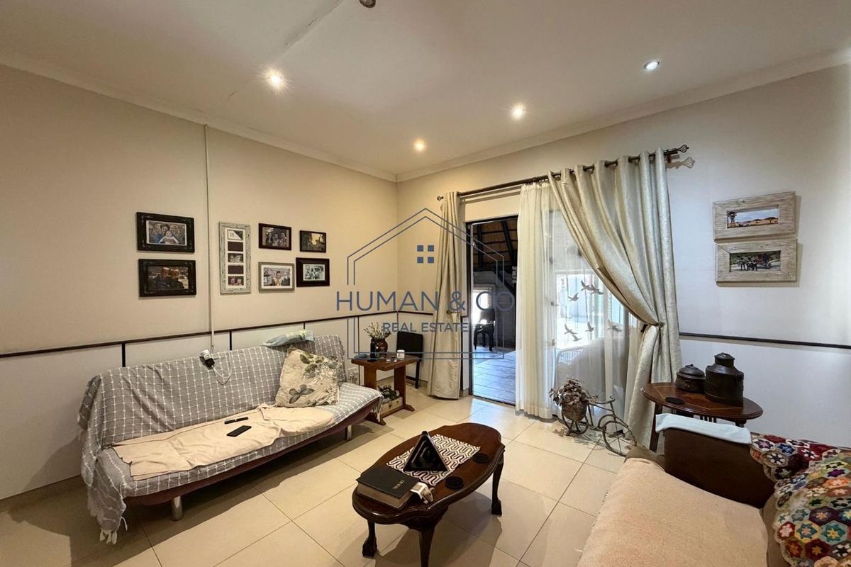 A living room featuring tiled flooring, recessed downlights, and a sliding glass door providing access to an outdoor area.