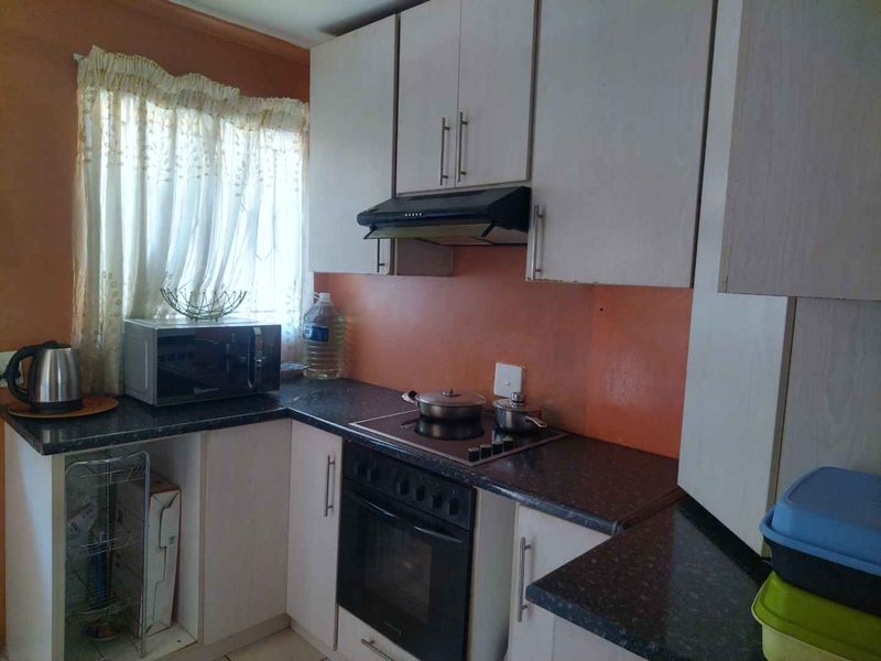 A functional kitchen featuring built-in cabinetry, laminate countertops, and integrated cooking appliances including an oven, hob, and extractor fan.
