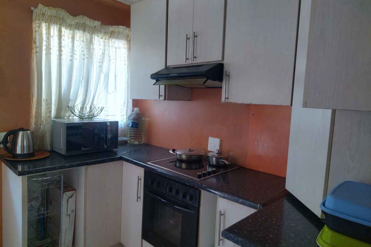 A functional kitchen featuring built-in cabinetry, laminate countertops, and integrated cooking appliances including an oven, hob, and extractor fan.