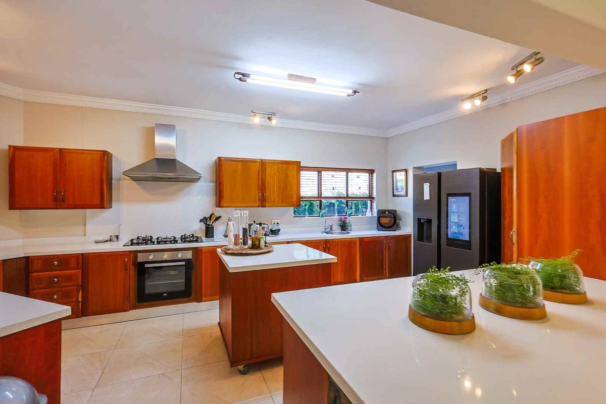 Spacious kitchen featuring wooden cabinetry, white countertops, a central island, stainless steel extractor fan, and built-in oven.