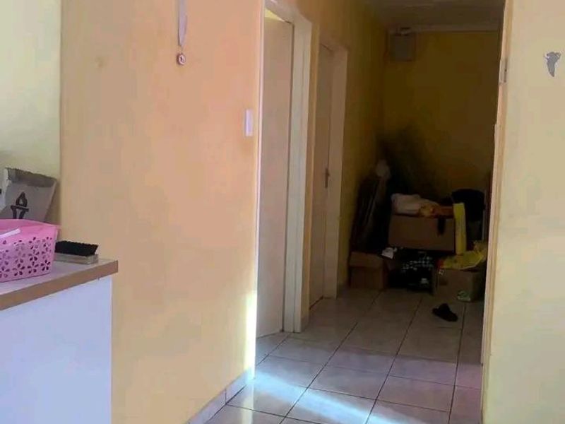 A narrow interior hallway featuring tiled flooring and access to multiple rooms, currently showing signs of wear and requiring cosmetic updates.