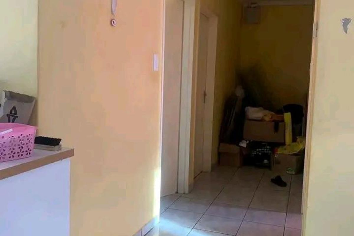A narrow interior hallway featuring tiled flooring and access to multiple rooms, currently showing signs of wear and requiring cosmetic updates.