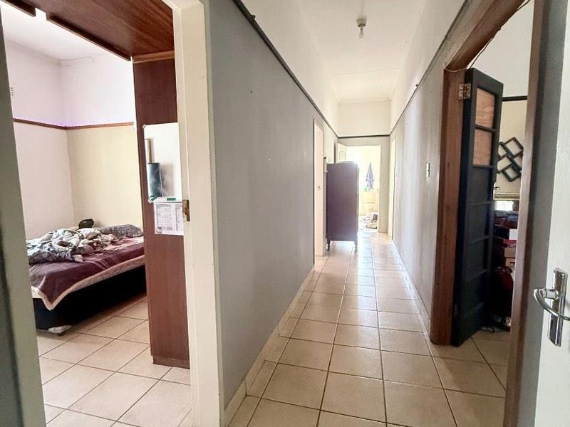 A functional hallway with tiled flooring providing access to adjacent bedrooms, featuring neutral wall tones and traditional wooden door frames.