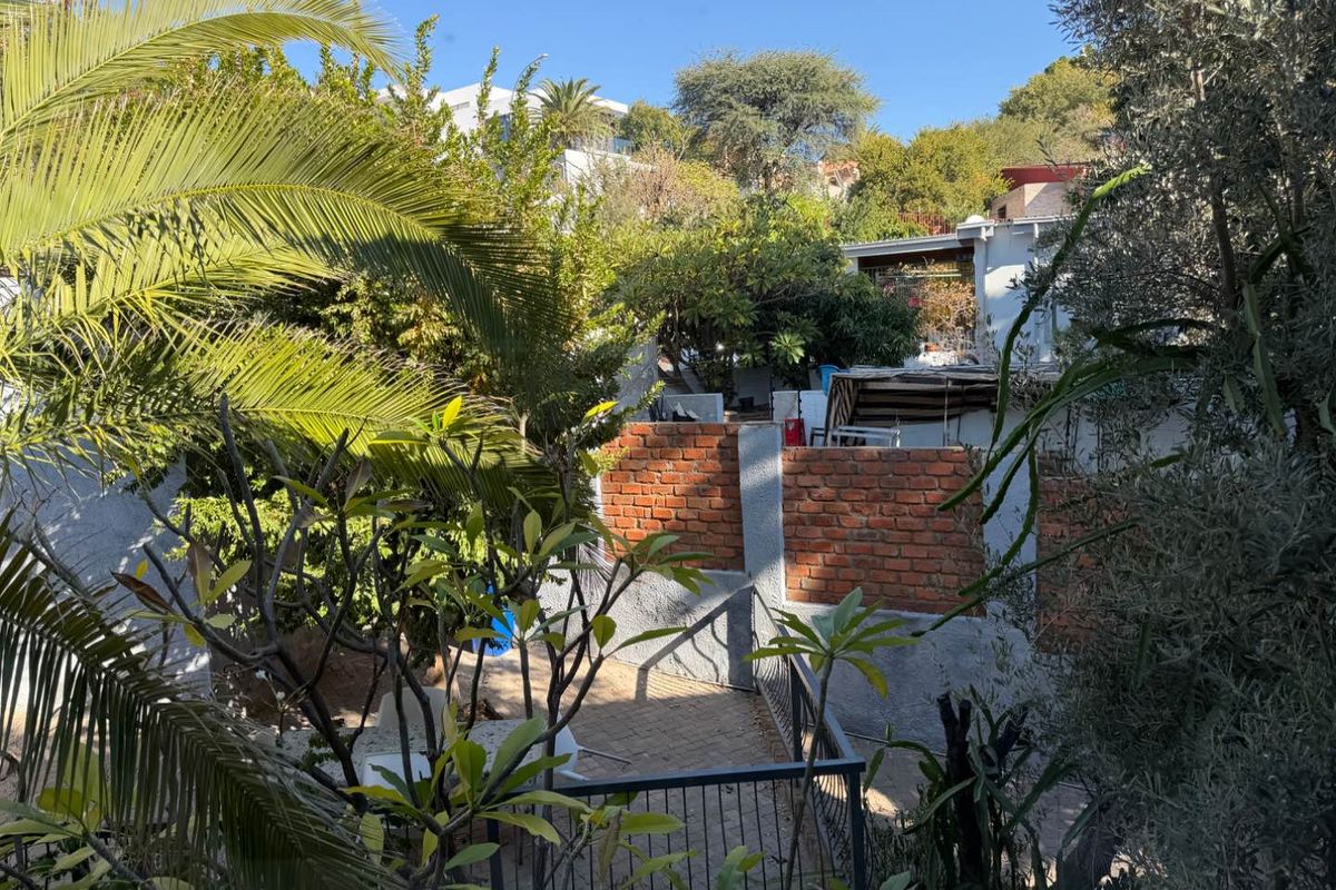 A rear garden area featuring a paved patio, brick boundary walls, and established greenery, offering a private outdoor space.