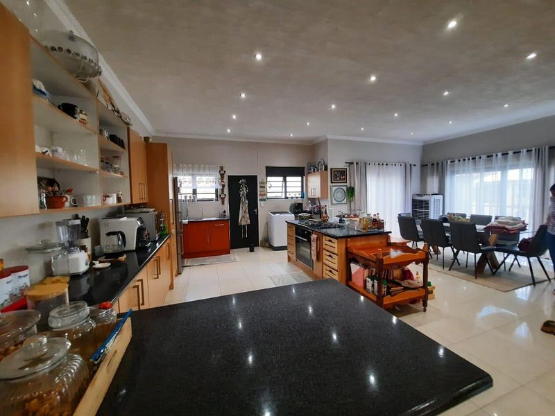 Spacious open-plan kitchen and dining area featuring granite countertops, modern cabinetry, and recessed lighting, creating a functional and inviting living space.