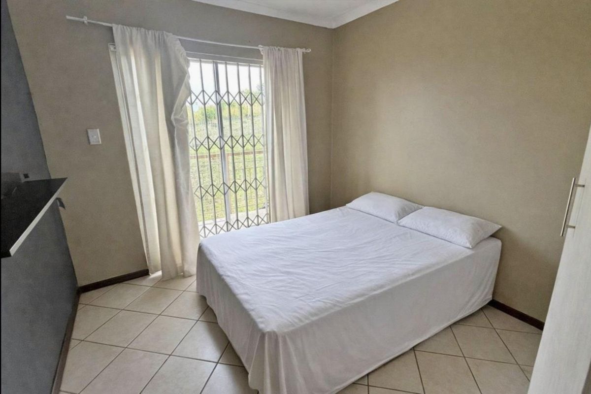 A bedroom featuring tiled flooring and a sliding glass door with a security gate, providing access to the exterior.