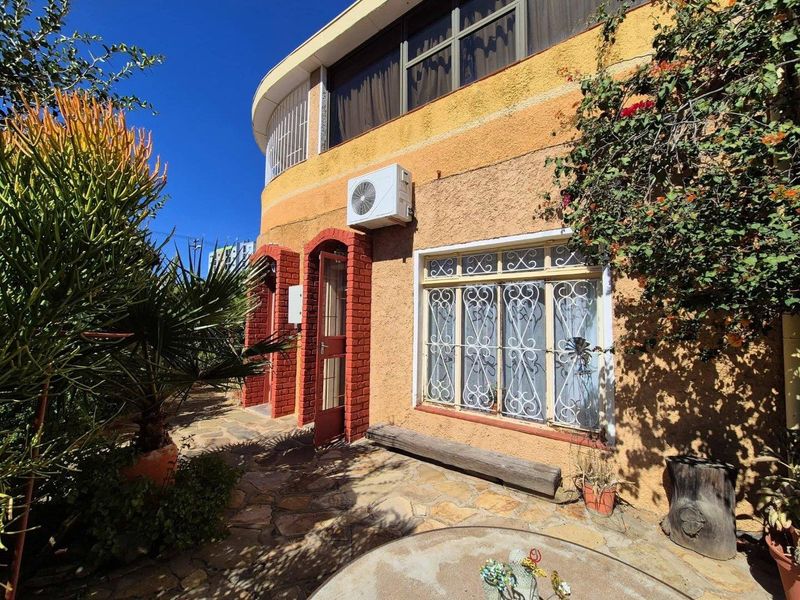Rear exterior view of the apartment featuring stone paving, a textured facade, and a mounted air conditioning unit.