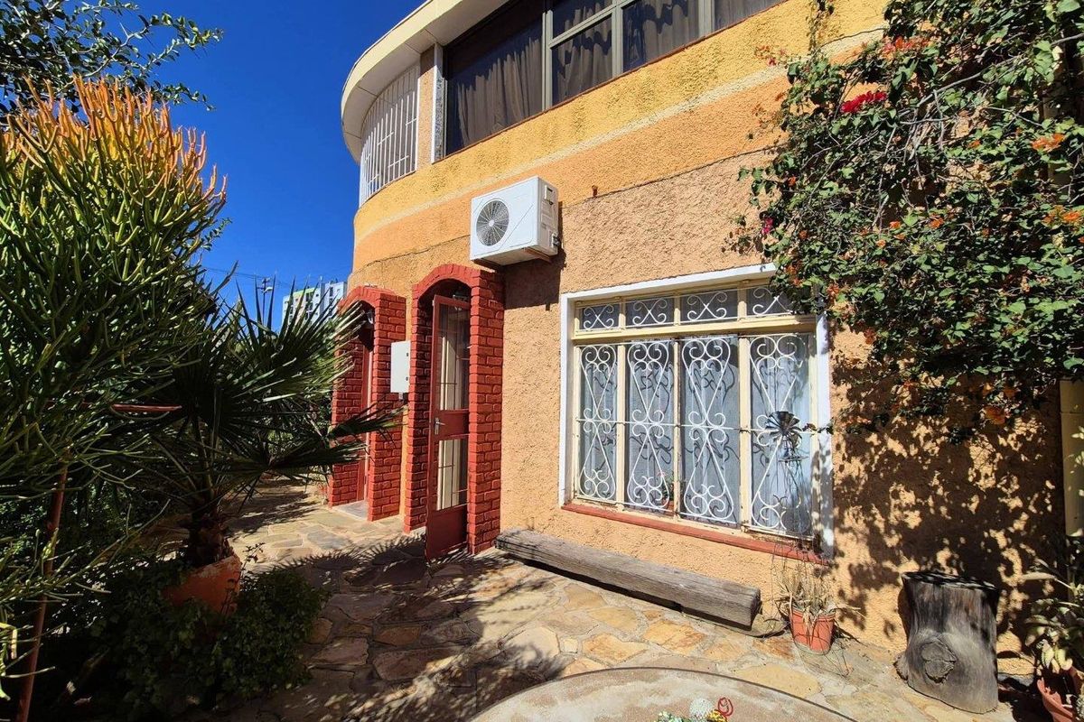 Rear exterior view of the apartment featuring stone paving, a textured facade, and a mounted air conditioning unit.