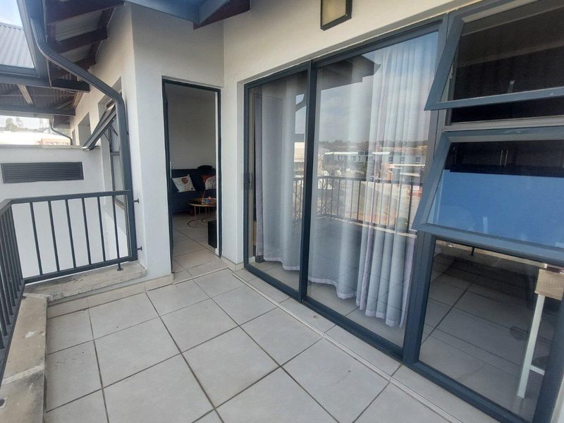 A covered balcony featuring tiled flooring, a metal balustrade, and large sliding glass doors providing access to the interior living space.