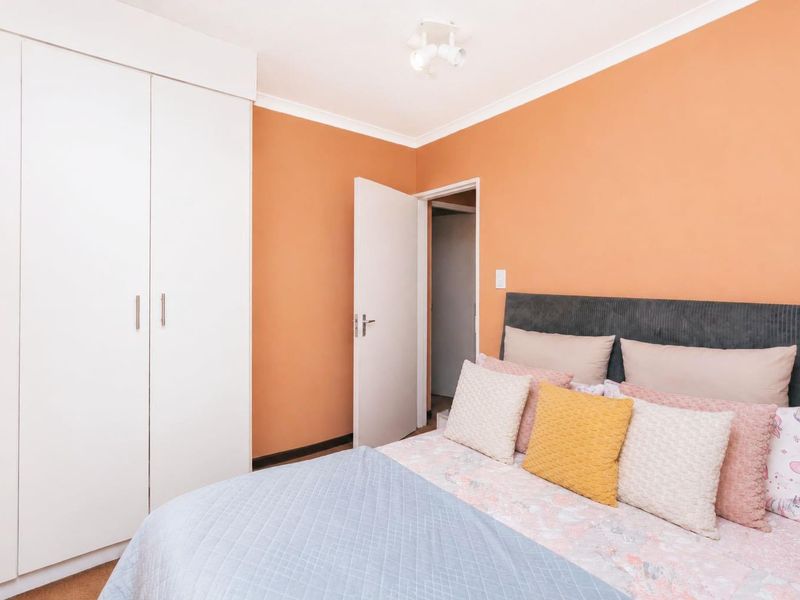 A bedroom featuring a built-in wardrobe, orange-toned walls, and a ceiling light fixture.