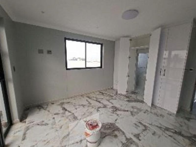 A bright, empty bedroom featuring modern marble-look floor tiles, built-in cupboards, and neutral grey walls, ready for personalization.