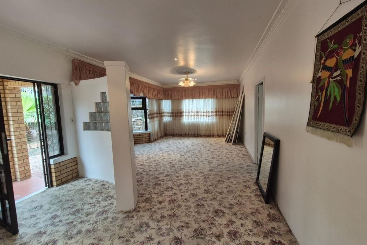 Spacious living area featuring a glass block partition, decorative ceiling rose, and direct access to the outdoor patio through a sliding glass door.
