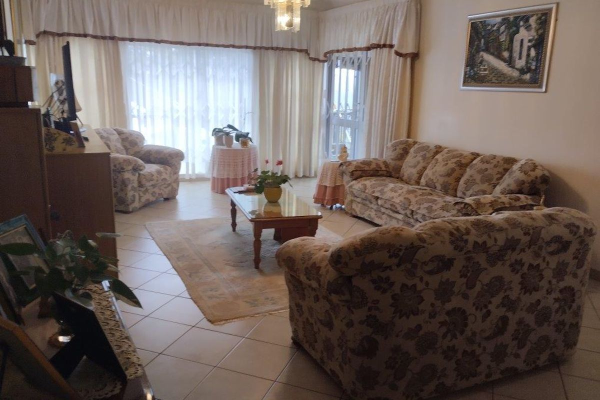 A spacious living room featuring tiled flooring and large sliding glass doors that provide access to the exterior, offering a bright and functional living space.