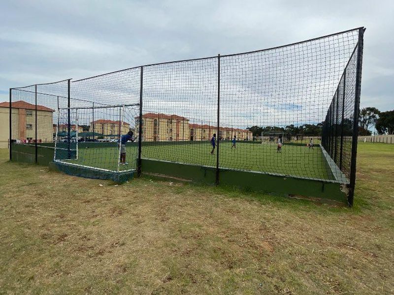 Outdoor sports facility featuring a fenced-in artificial turf pitch, suitable for recreational soccer or multi-sport activities within the apartment complex.