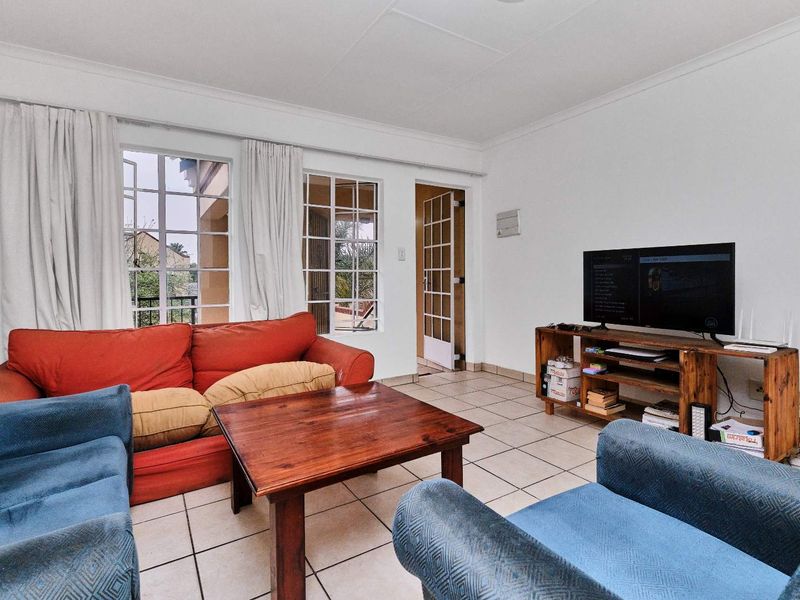 A living room featuring tiled flooring, coved ceilings, and multiple french doors providing natural light and access to the exterior.