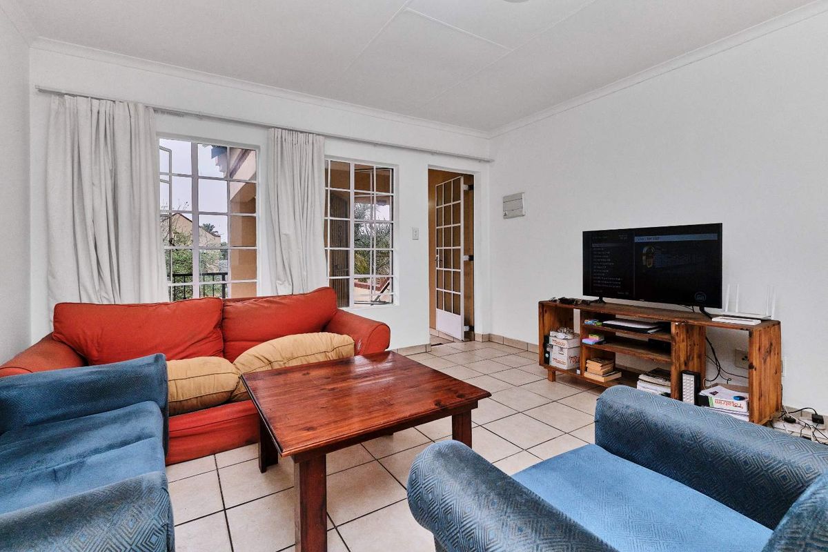 A living room featuring tiled flooring, coved ceilings, and multiple french doors providing natural light and access to the exterior.