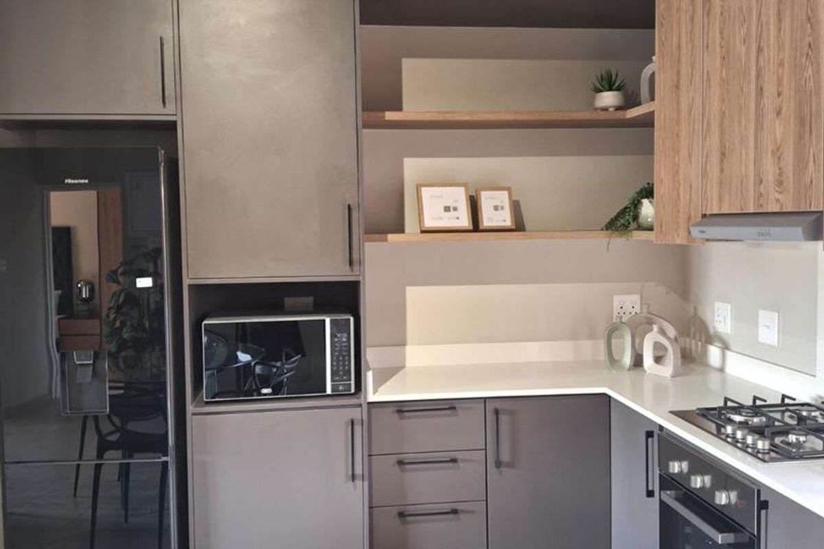 Modern kitchen featuring sleek grey cabinetry, wood-tone accents, quartz countertops, integrated appliances, and a gas hob with an extractor fan.