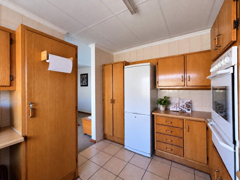 A functional kitchen featuring traditional wooden cabinetry, tiled splashbacks, tiled flooring, and built-in oven, offering a classic and practical layout.