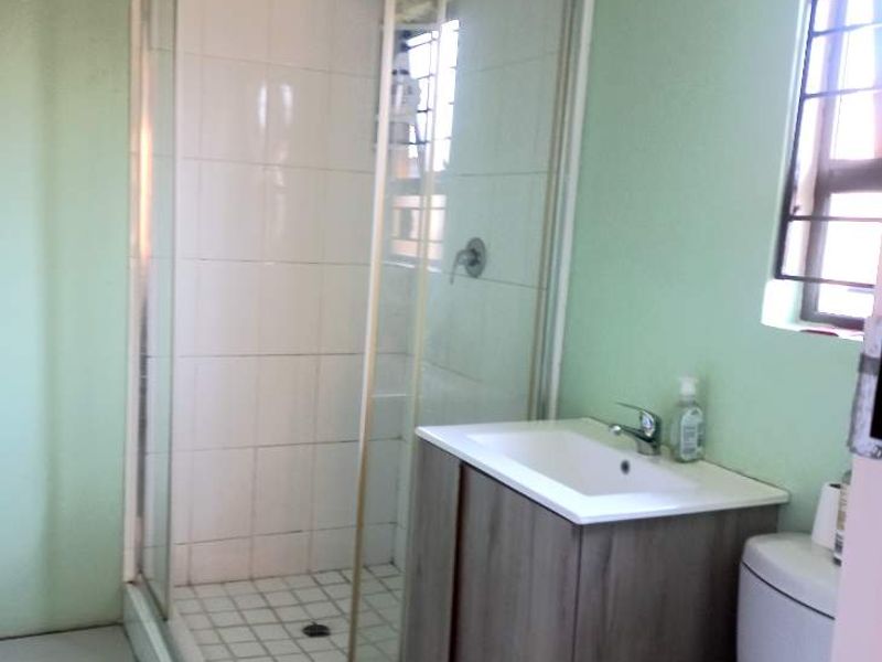A functional bathroom featuring a corner shower enclosure, a modern vanity unit with a basin, and a standard toilet.