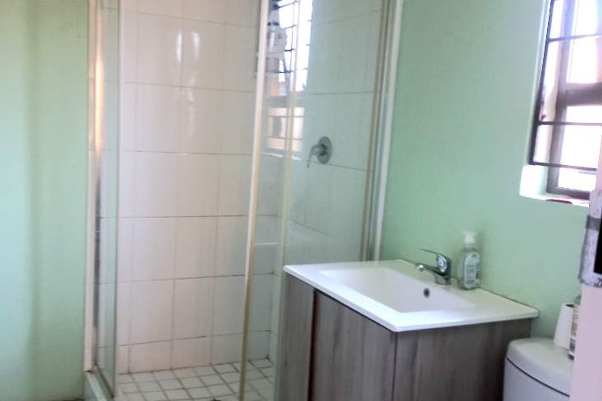 A functional bathroom featuring a corner shower enclosure, a modern vanity unit with a basin, and a standard toilet.