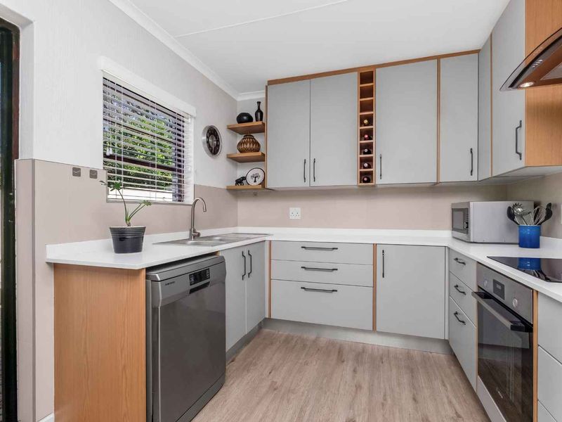 A modern, well-maintained kitchen featuring light grey cabinetry, wood-look flooring, integrated appliances, and a functional layout with ample counter space.