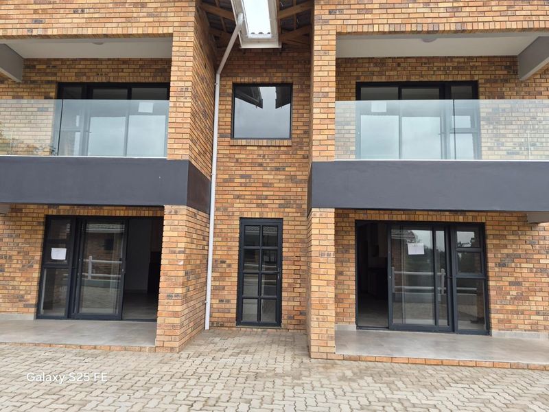 Modern apartment exterior featuring face brick construction, glass balustrades, and sliding door access to ground floor patios.