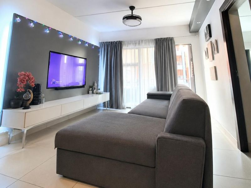 A modern living room featuring tiled floors, a feature wall, and a sliding glass door leading to an outdoor area.