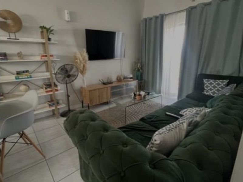 A comfortable living room featuring tiled flooring, a ceiling light fixture, and a sliding glass door providing access to the exterior.