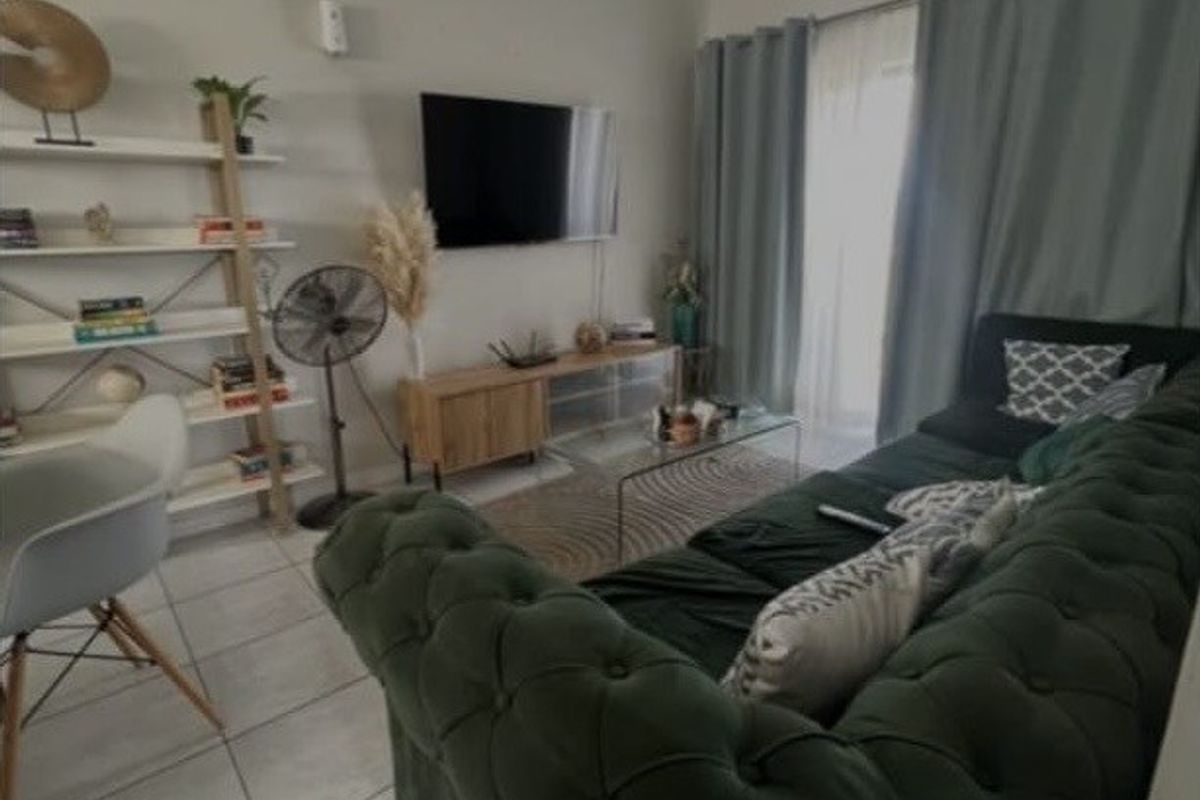 A comfortable living room featuring tiled flooring, a ceiling light fixture, and a sliding glass door providing access to the exterior.