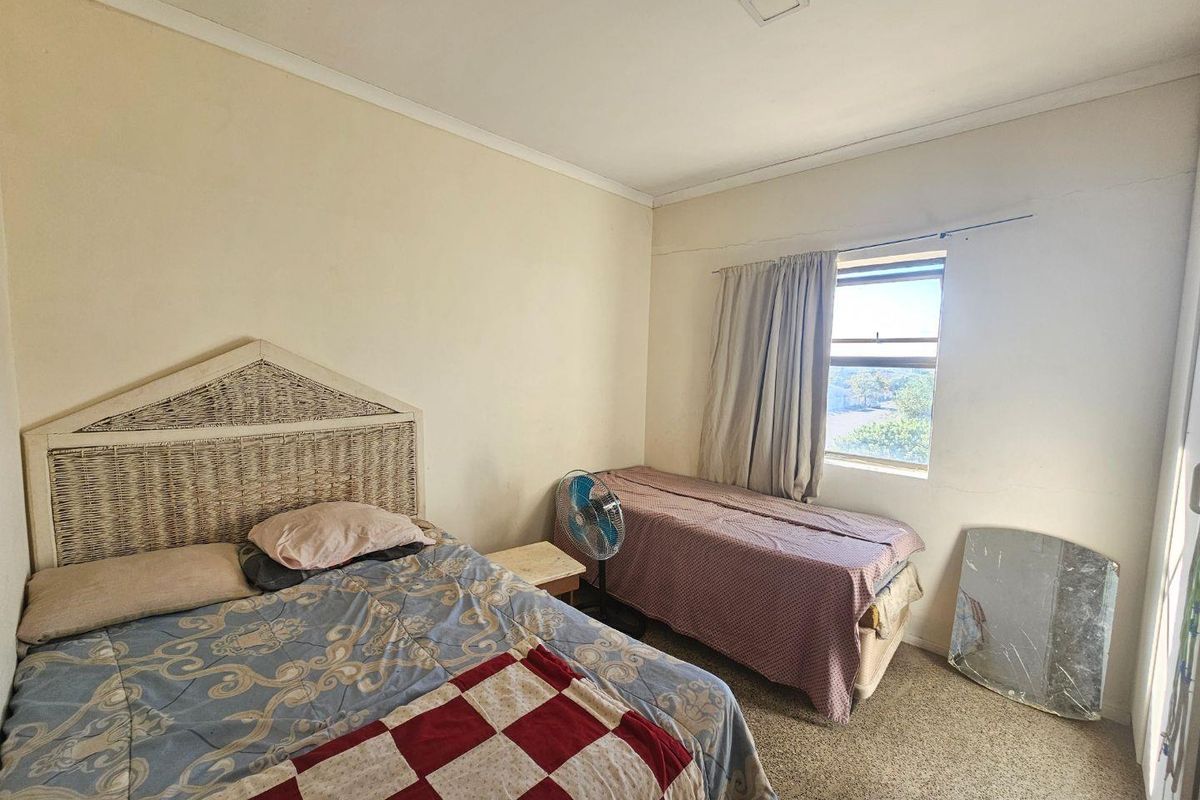 A bedroom featuring carpeted flooring, a single window with curtain track, and standard ceiling lighting.