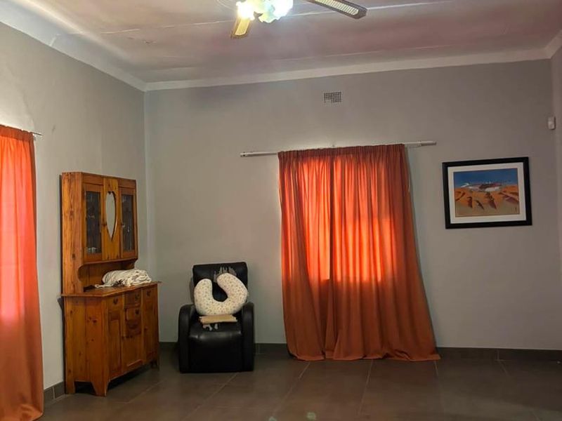 A living room featuring tiled flooring, a ceiling fan, and coved ceiling details, providing a functional space with potential for modernization.