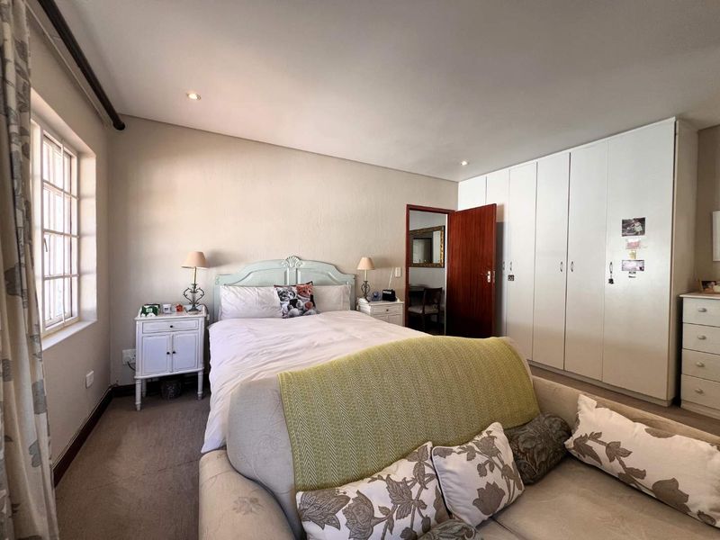A spacious bedroom featuring built-in cupboards, recessed downlighting, and a large window, providing a functional and comfortable living space.