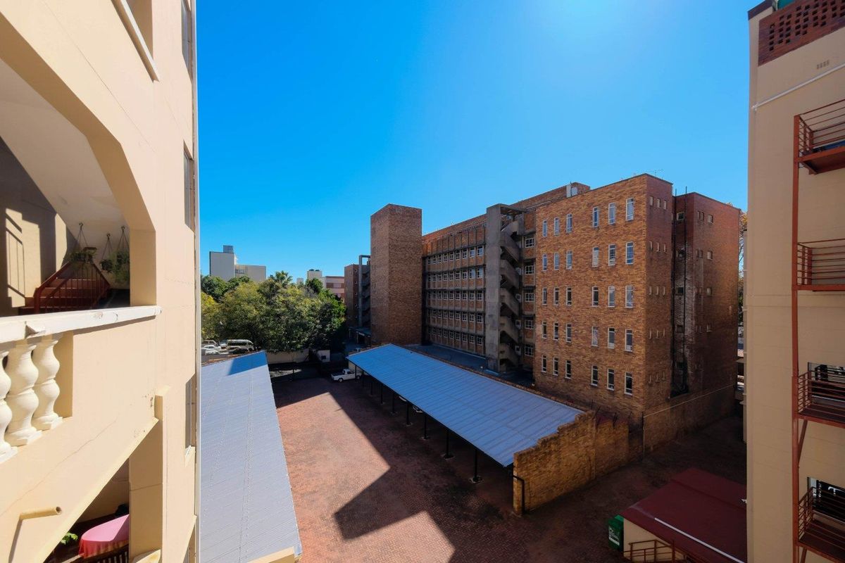 An elevated view of the apartment complex rear courtyard featuring brick building facades and covered parking structures.