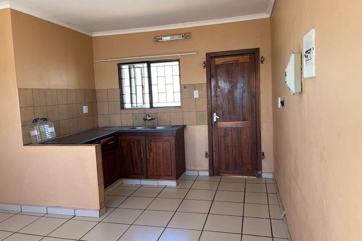 A functional kitchen space featuring built-in wooden cabinetry, tiled backsplash, and tiled flooring, ready for a modern update to enhance its aesthetic appeal.