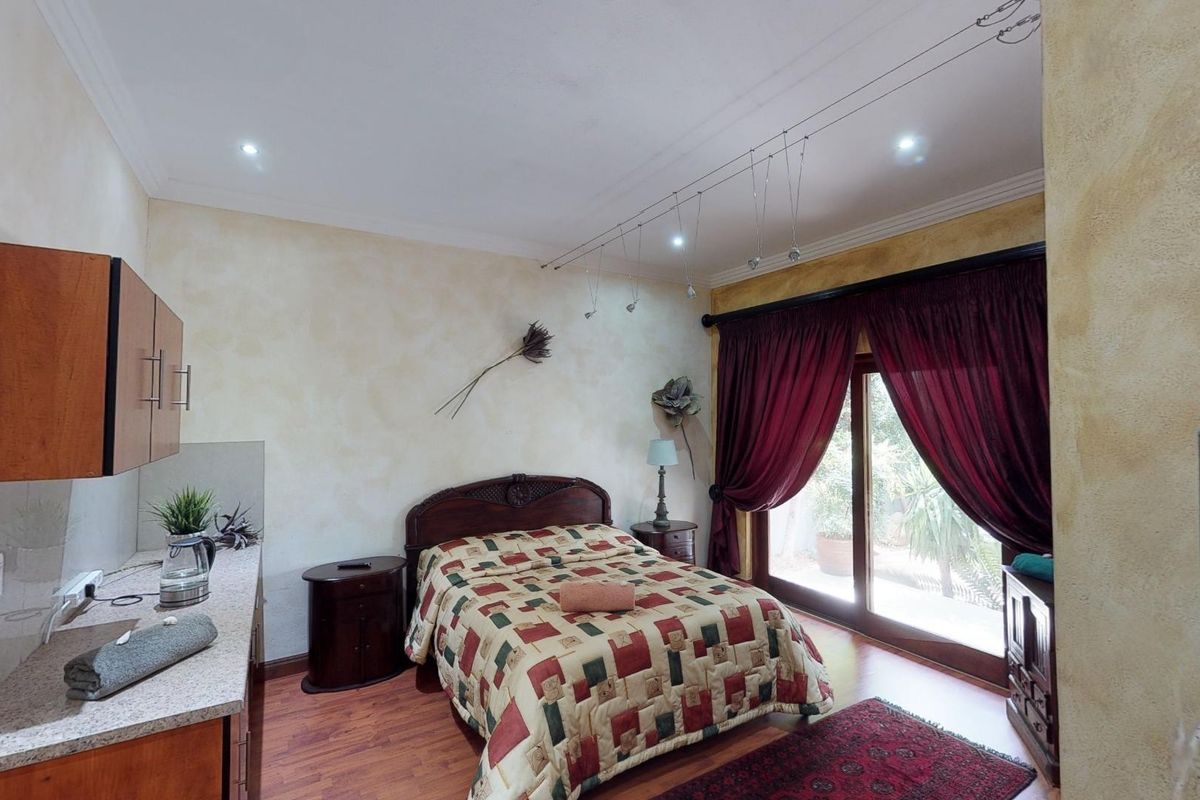A bedroom featuring laminate flooring, recessed lighting, and a sliding glass door providing access to the exterior, complemented by built-in cabinetry and stone countertops.