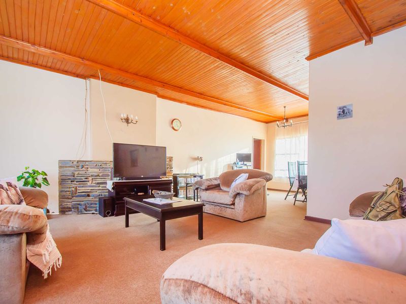Spacious living room featuring a distinctive timber-clad vaulted ceiling and a stone-accented fireplace, offering a warm and traditional atmosphere.