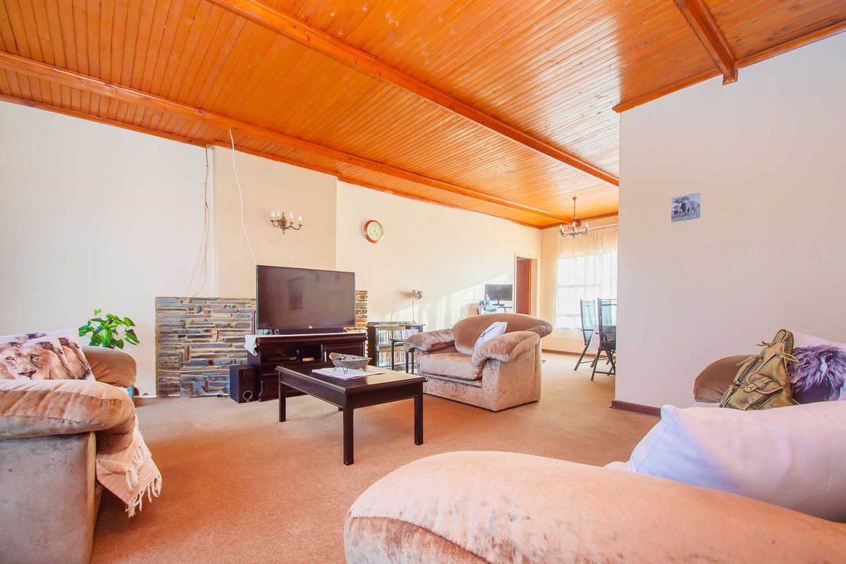 Spacious living room featuring a distinctive timber-clad vaulted ceiling and a stone-accented fireplace, offering a warm and traditional atmosphere.
