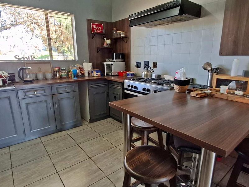 A functional kitchen featuring dark cabinetry, a gas hob with extractor fan, tiled backsplash, and a built-in breakfast counter.