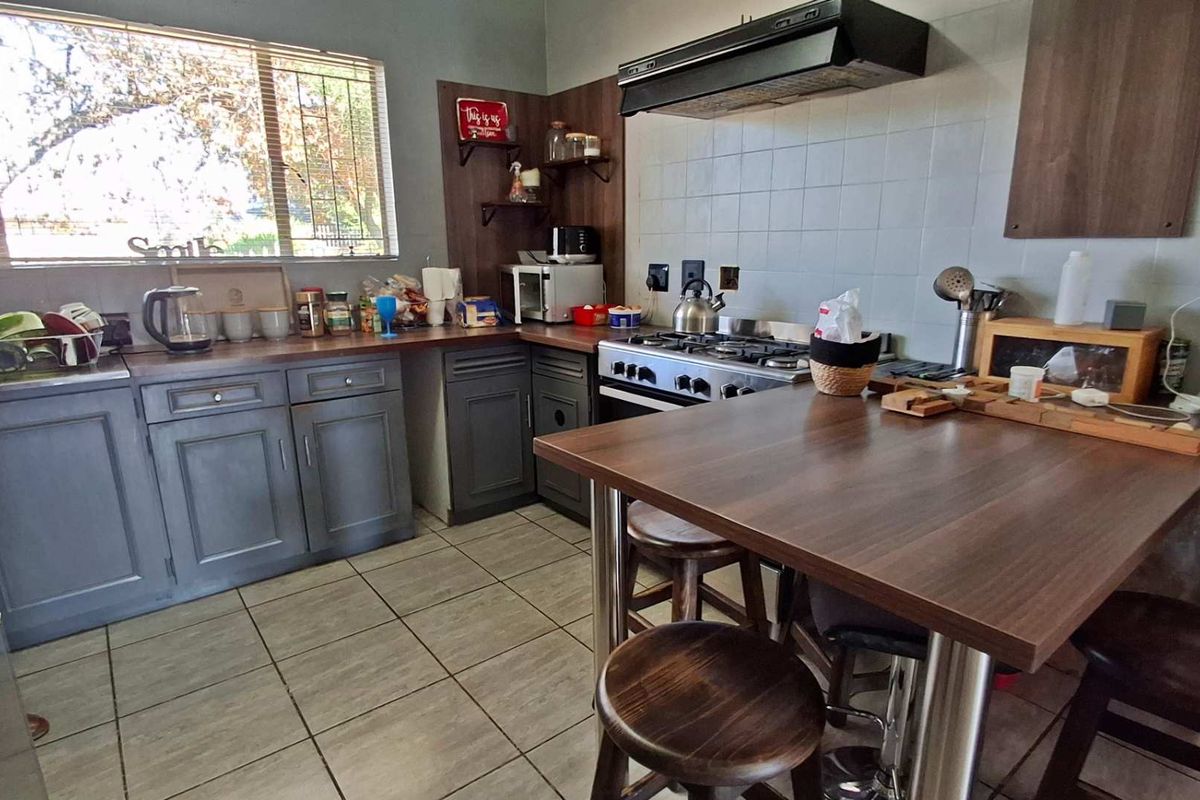 A functional kitchen featuring dark cabinetry, a gas hob with extractor fan, tiled backsplash, and a built-in breakfast counter.