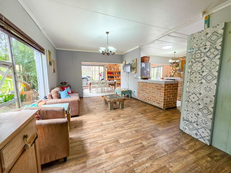 Open plan living area featuring laminate wood flooring, an exposed brick breakfast bar, and a decorative feature door, connecting to a dining space.