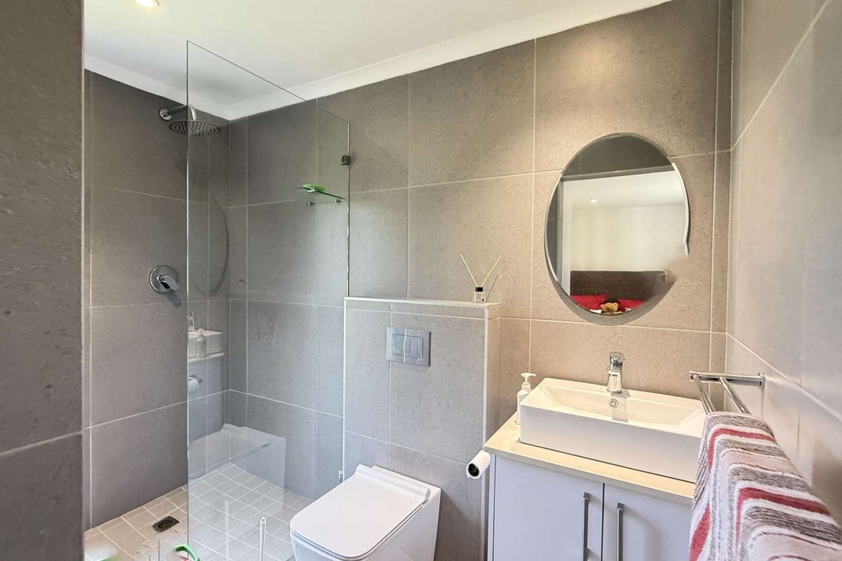 Modern bathroom featuring a walk-in glass shower, wall-mounted toilet, and a contemporary vanity with a vessel sink.