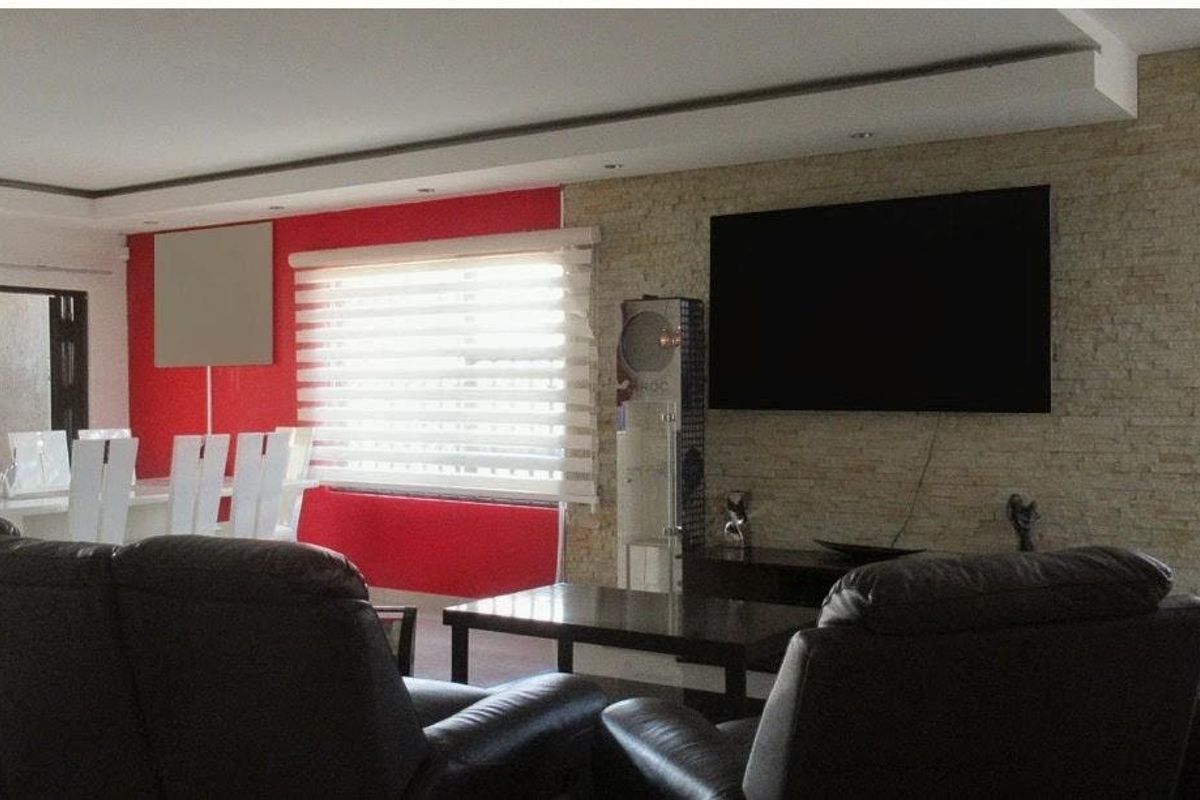 Spacious living room featuring a textured stone cladding accent wall, recessed ceiling lighting, and large sliding glass doors providing natural light.