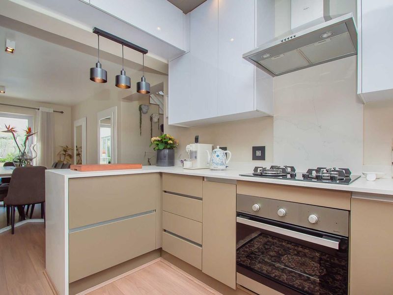 Modern open-plan kitchen featuring sleek cabinetry, quartz countertops, integrated gas hob, and oven, seamlessly flowing into the adjacent dining area.