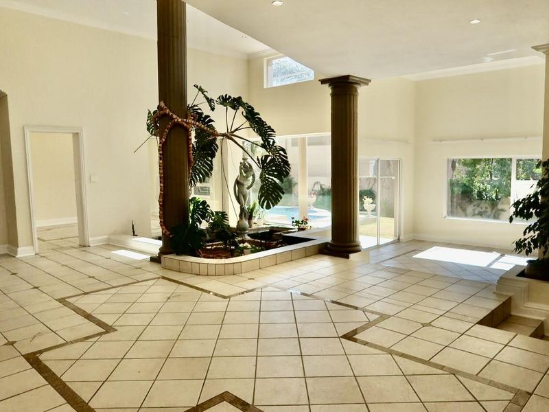 Spacious open-plan living area featuring tiled floors, decorative columns, and a central indoor water feature with direct access to the pool area.