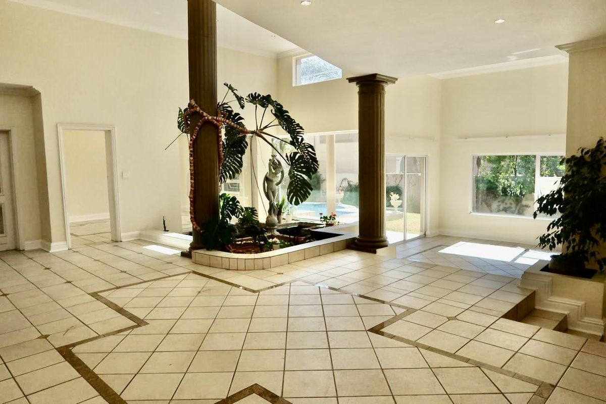 Spacious open-plan living area featuring tiled floors, decorative columns, and a central indoor water feature with direct access to the pool area.
