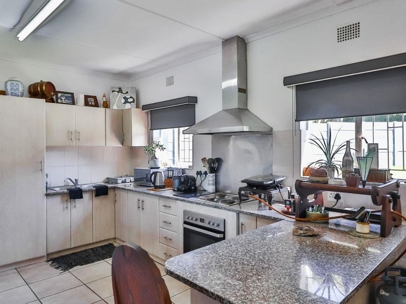 Functional kitchen featuring granite countertops, built-in cabinetry, stainless steel oven and extractor fan, and tiled flooring.