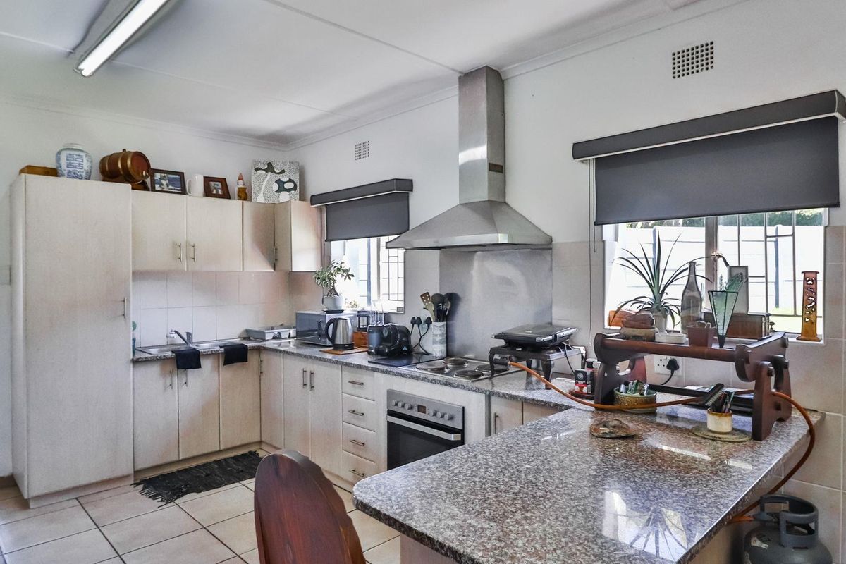 Functional kitchen featuring granite countertops, built-in cabinetry, stainless steel oven and extractor fan, and tiled flooring.