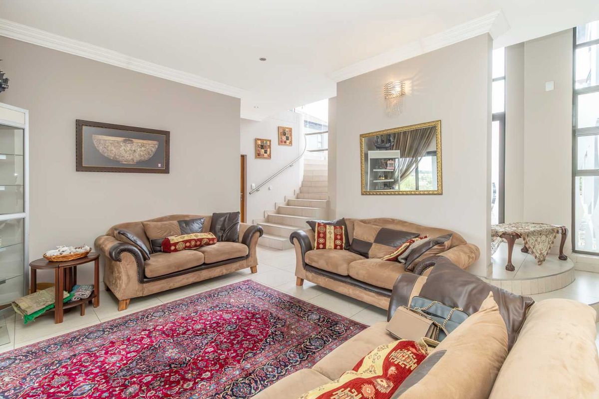 Spacious living area featuring tiled flooring, crown molding, and a staircase leading to the upper level with large windows providing natural light.