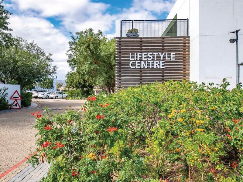 Exterior view of the apartment complex lifestyle centre featuring a modern timber slat facade, paved driveway, and well-maintained landscaped gardens.